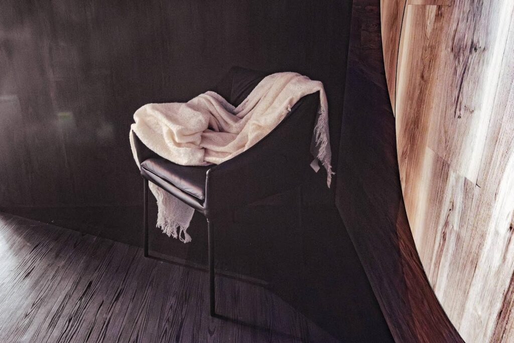 Piso vinílico preto madeira ebanizada aplicado em ambiente corporativo elegante com poltrona e acabamento sofisticado.